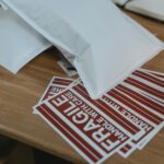 Solutions Close-up view of mailing supplies with fragile stickers on a wooden table.
